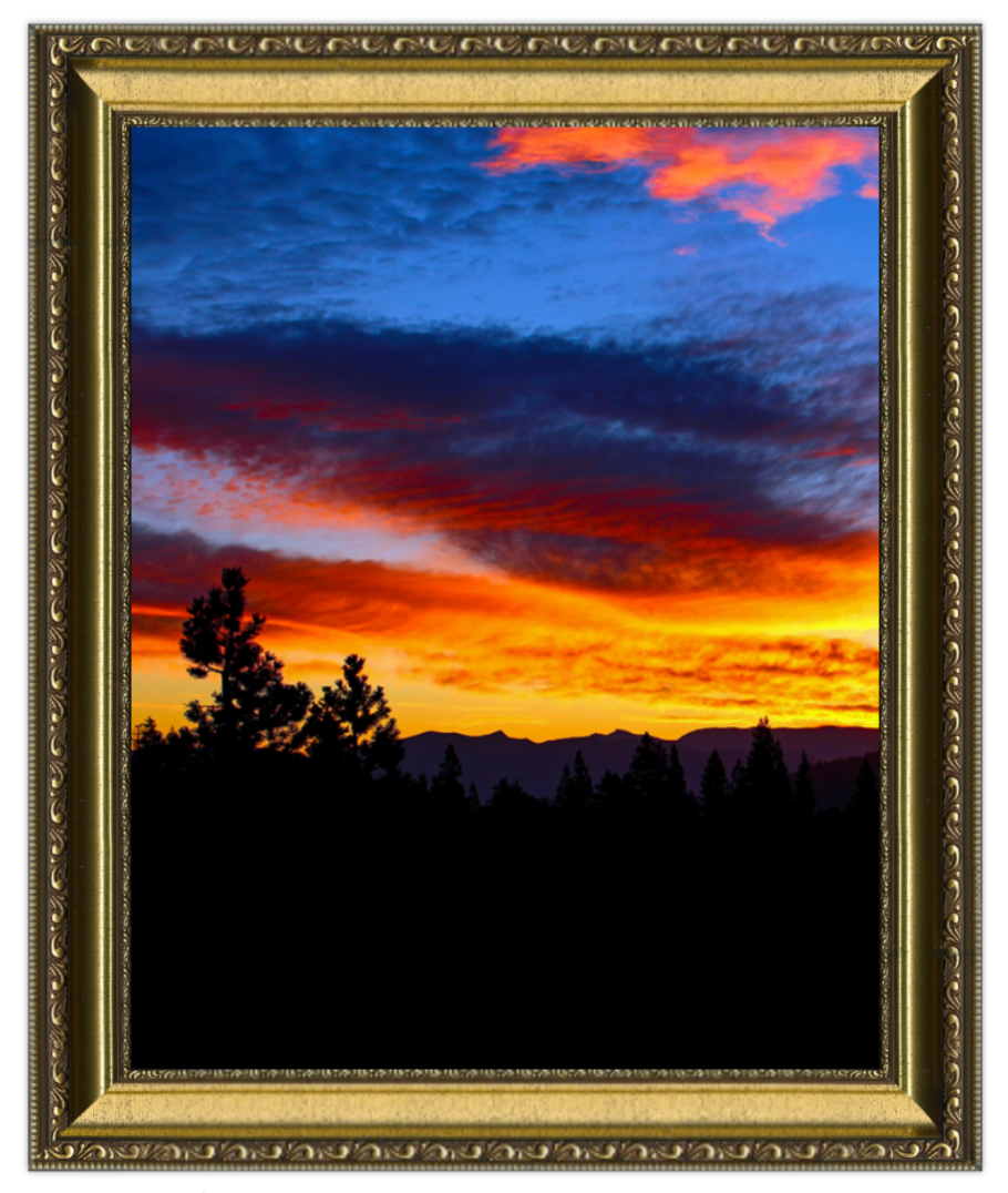 Framed photograph of a sunset with silhouetted trees and mountains
