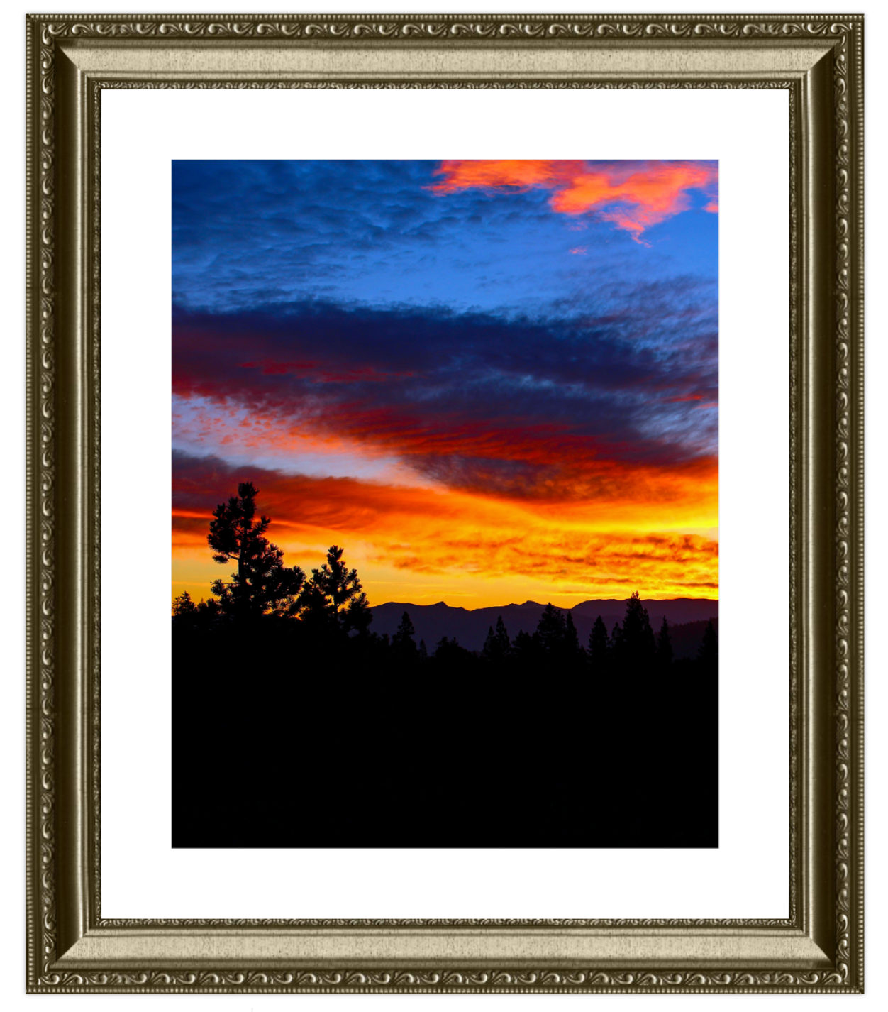 Framed photograph of a sunset over a mountain range with silhouetted trees.