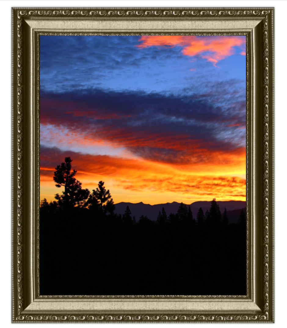 Framed photograph of a sunset with silhouetted trees and mountains