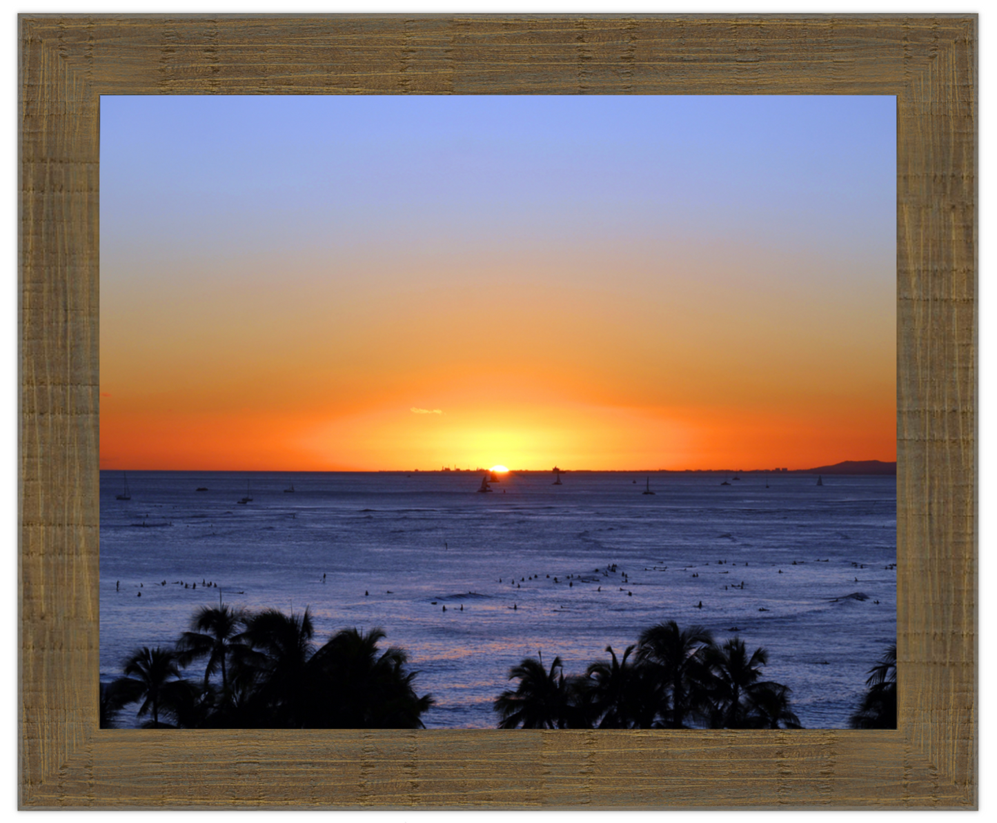 Sunset over the ocean with palm trees in the foreground