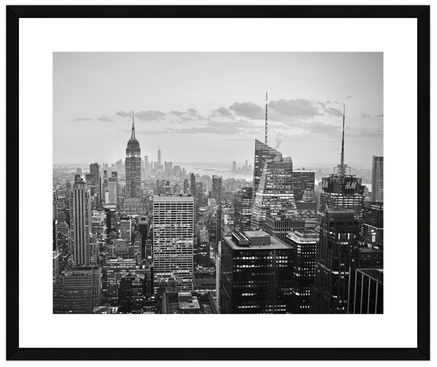 Black and white cityscape with tall buildings under a cloudy sky.
