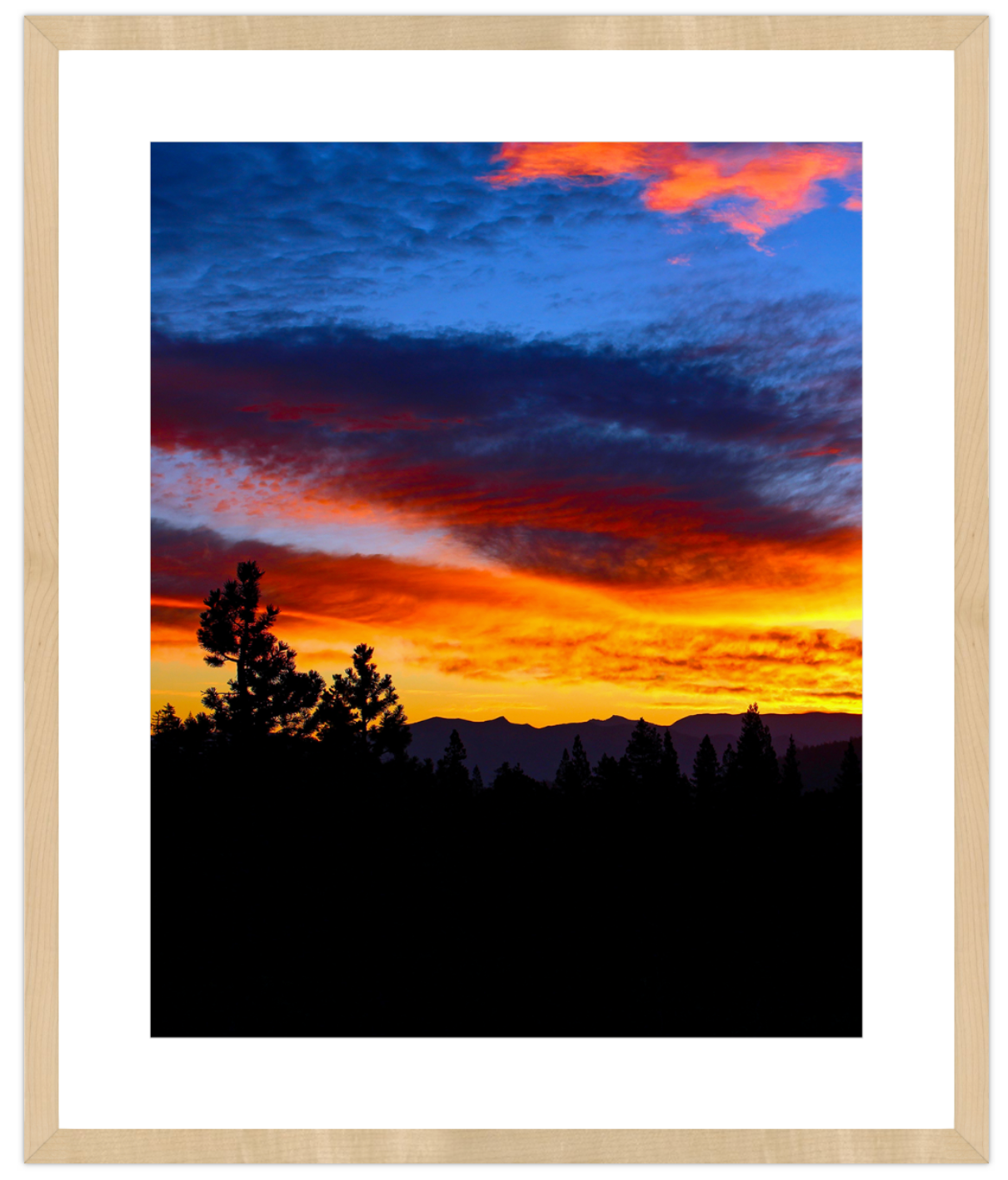 Framed photograph of a sunset with silhouetted trees and mountains