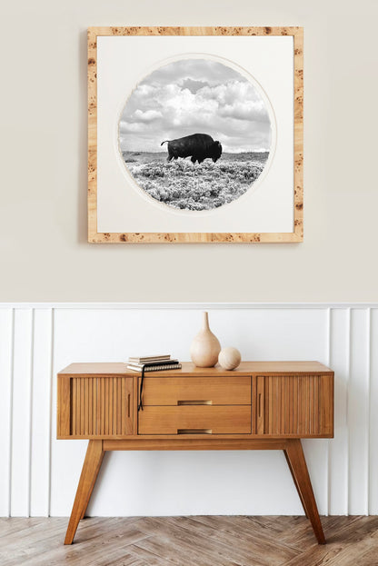 Framed black and white artwork of a buffalo on a wall above a wooden console table.