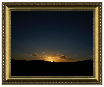 Sunset over a landscape with a decorative gold frame.