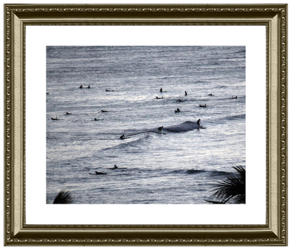 Framed black and white artwork of surfers in the ocean.