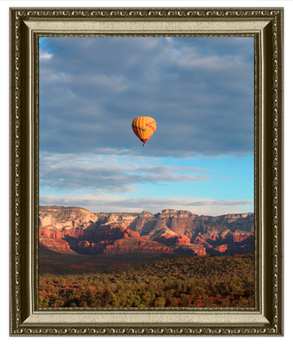 Hot air balloon over a canyon landscape with a decorative frame.