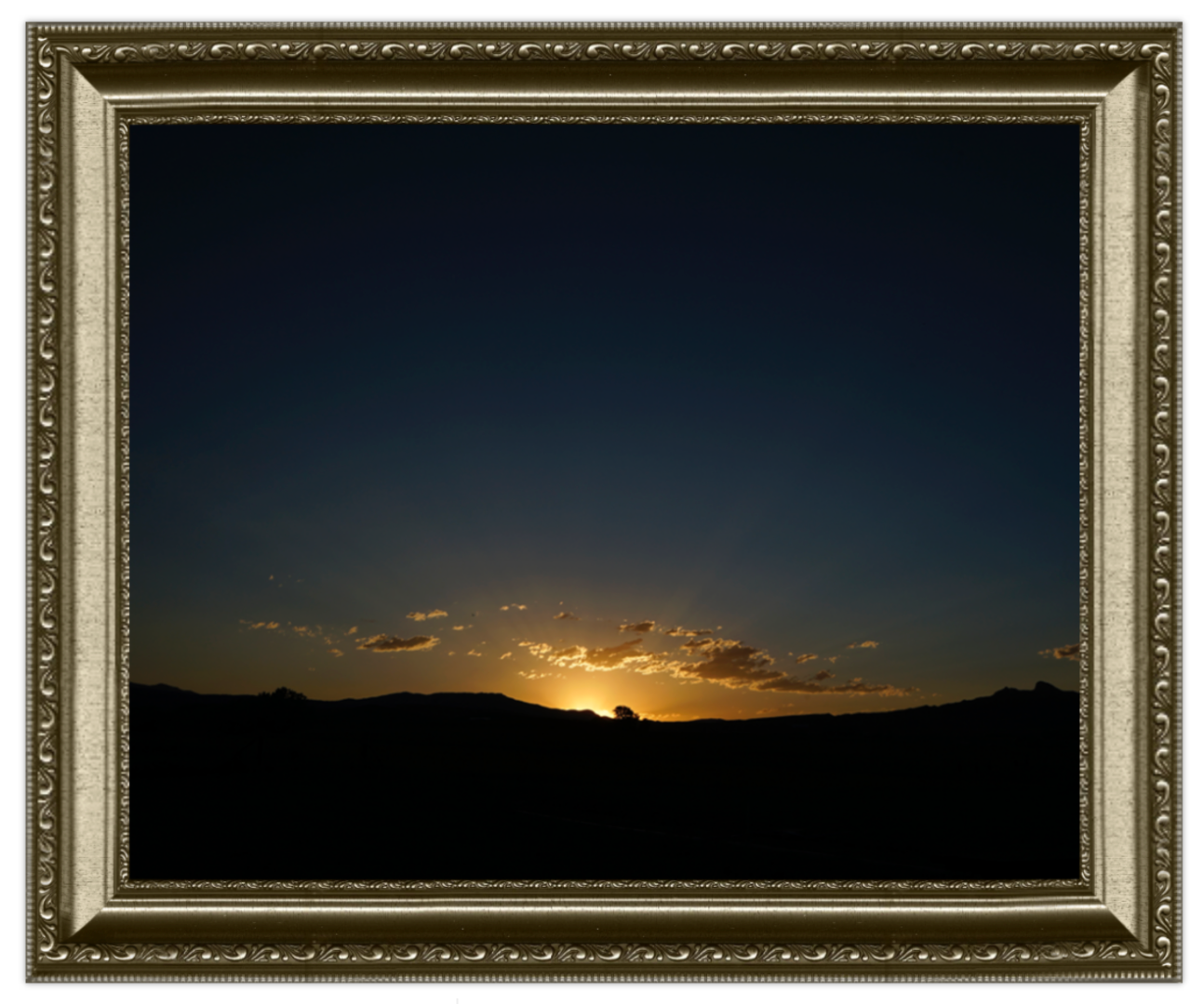 Framed landscape of a sunset over a mountain range with a decorative gold frame.