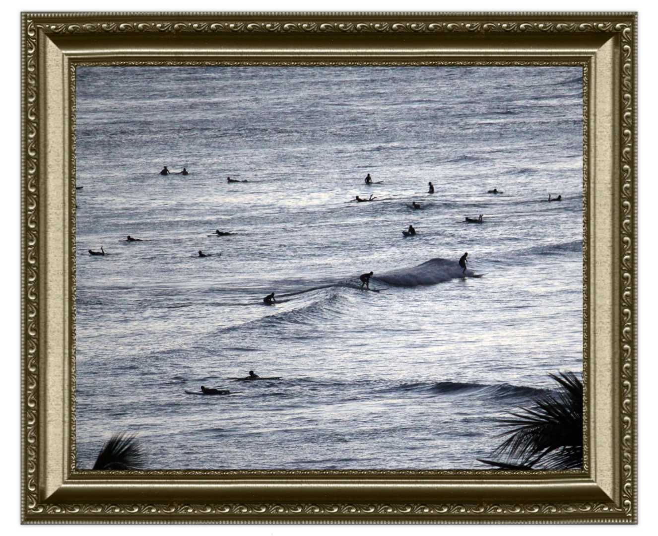 Framed artwork of  the ocean with surfers, framed in gold.