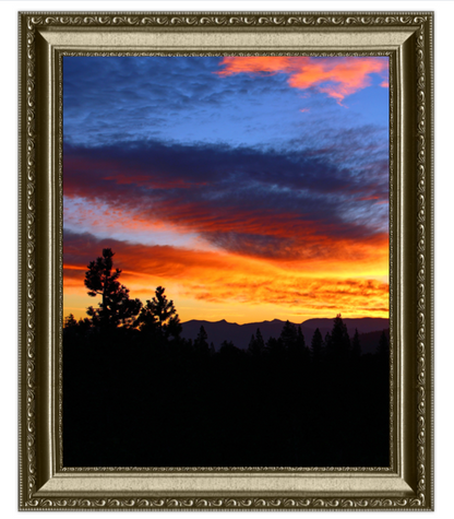 Framed photograph of a sunset with silhouetted trees and mountains