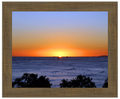 Sunset over the ocean with palm trees in the foreground