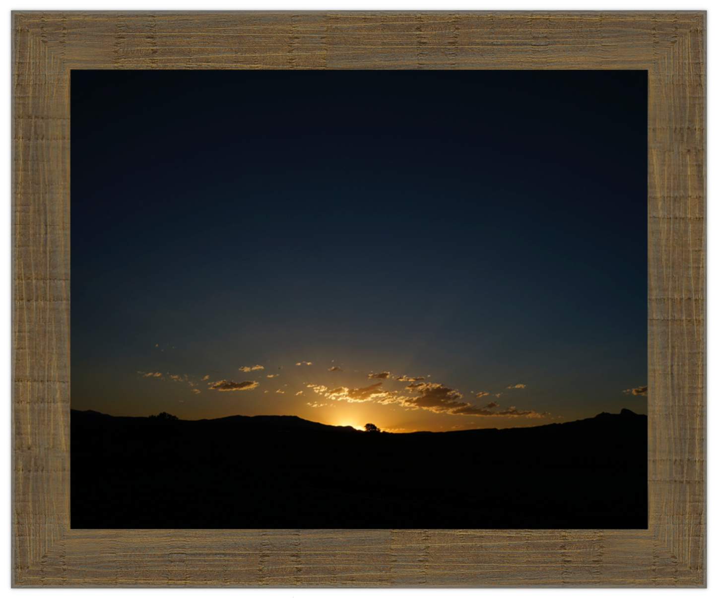 Sunset over a mountain range with a wooden frame