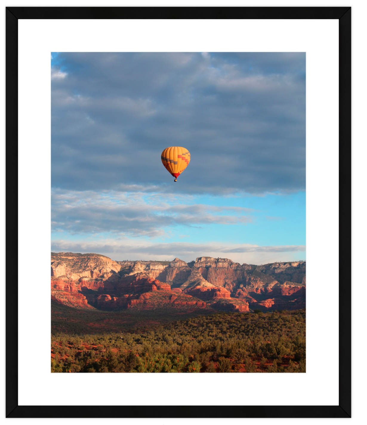 Hot air balloon floating above a desert landscape with mountains in the background
