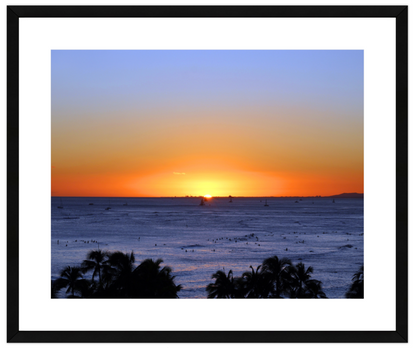 Sunset over the ocean with palm trees in the foreground