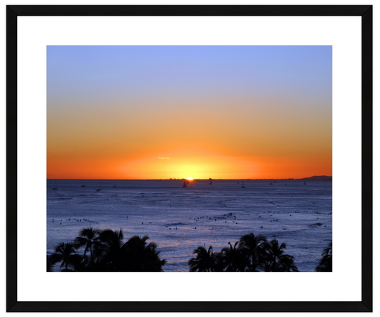 Sunset over the ocean with palm trees in the foreground