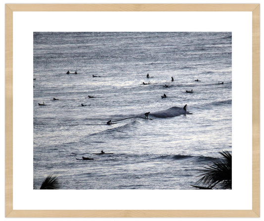 Black and white image of surfers in the ocean with a framed border.