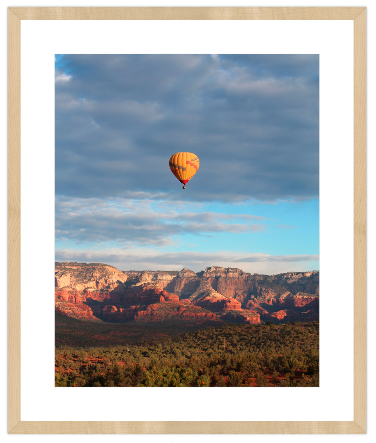 Hot air balloon floating over a desert landscape with mountains in the background