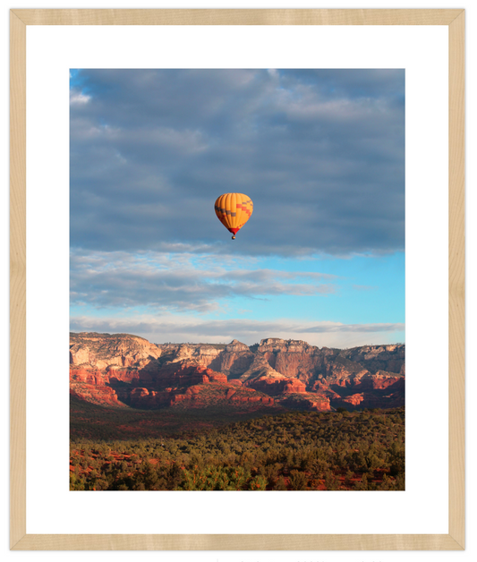 Hot air balloon floating over a desert landscape with mountains in the background