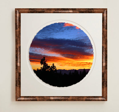 Framed circular artwork of a sunset with trees and mountainsA collection of framed artwork prints with a deckled edge appearance, displayed in two museum style frames named Light Burlwood and Dark Burlwood. The frames are pictured in various sizes with a white mat and clear acrylic front.